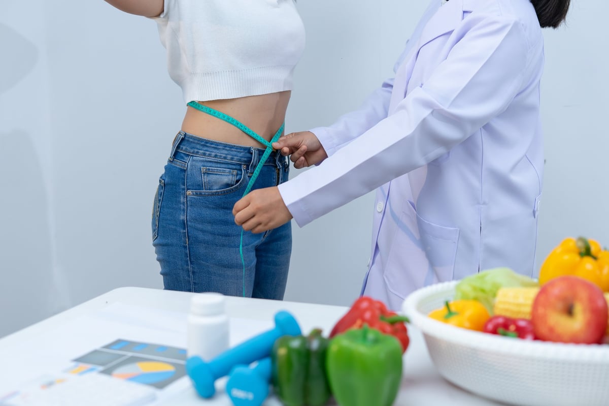 Nutritionist measuring woman's waist in health consultation for body composition analysis