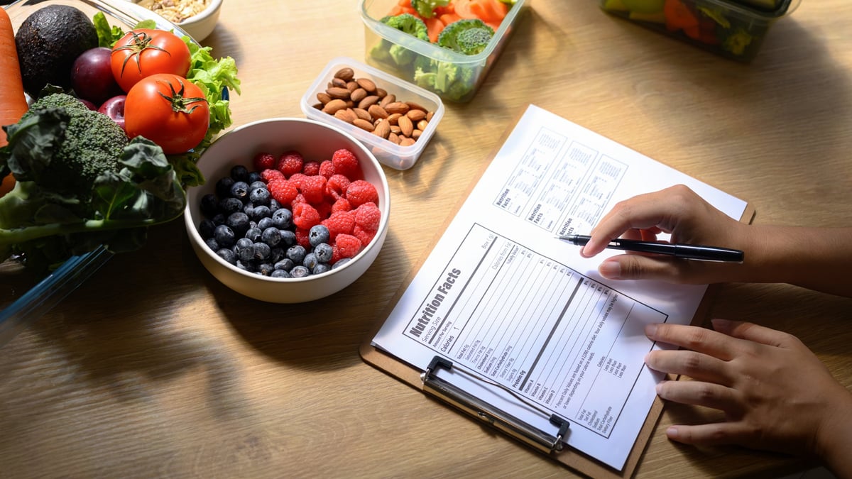 Nutritionist creating healthy meal plan with fresh fruits, vegetables and nuts on the table